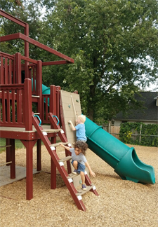 2 boys playing together on the playground at the Stepping Stones Child Care